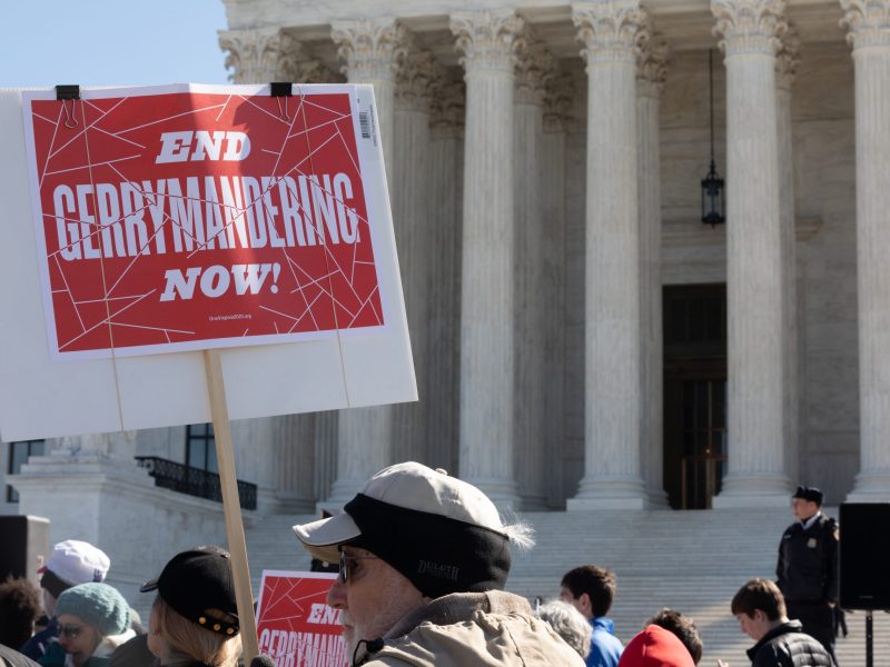 Protesters outside the Supreme Court building with a sign reading "End Gerrymandering Now!"
