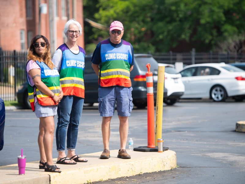 Clinic escorts stand in the parking lot as anti-abortion demonstrators hold a protest outside the Planned Parenthood Reproductive Health Services Center in St. Louis, Missouri