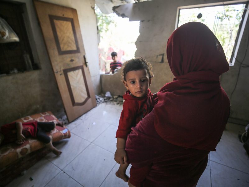 A Palestinian mother holding a child in a damaged house in Beit Hanoun, Gaza