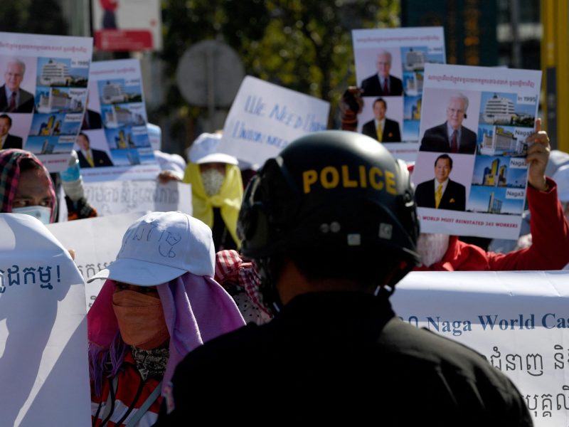 A police officer blocks workers from the NagaWorld casino holding placards during a protest outside the National Assembly building in Phnom Penh on January 4, 2022.