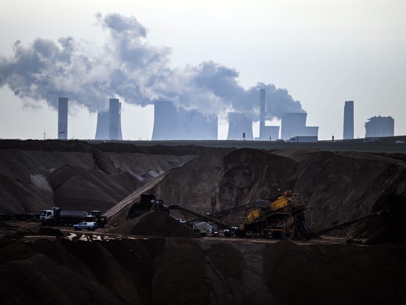 Mining machines work in the Garzweiler open pit lignite mine, with the Neurath lignite-fired power plant in the background