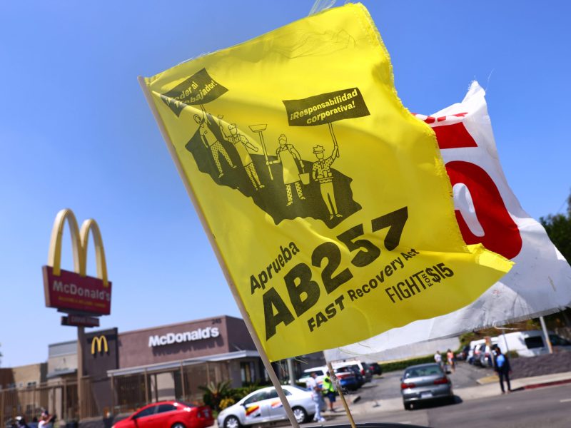 Flags are flown at a car caravan and rally of fast food workers and supporters for passage of AB 257.
