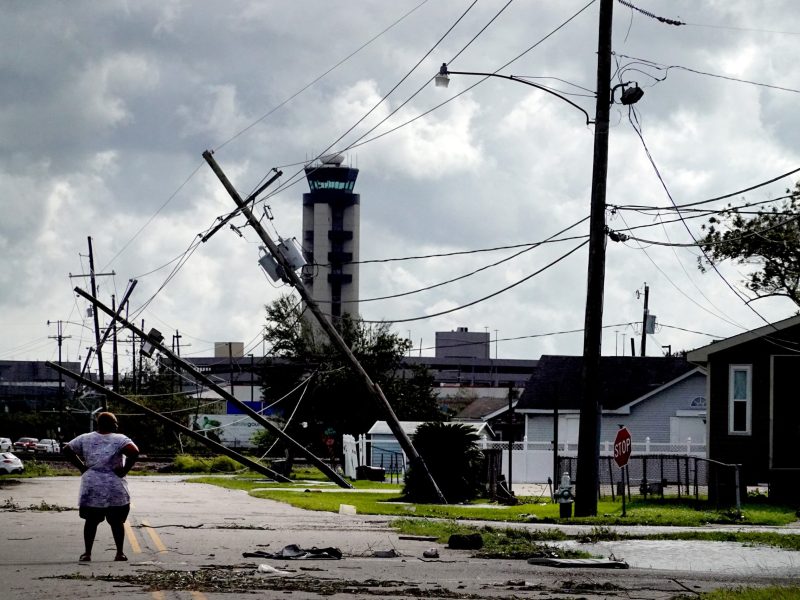 ﻿A woman stands in the street and surveys the damage to a neighborhood caused by Hurricane Ida