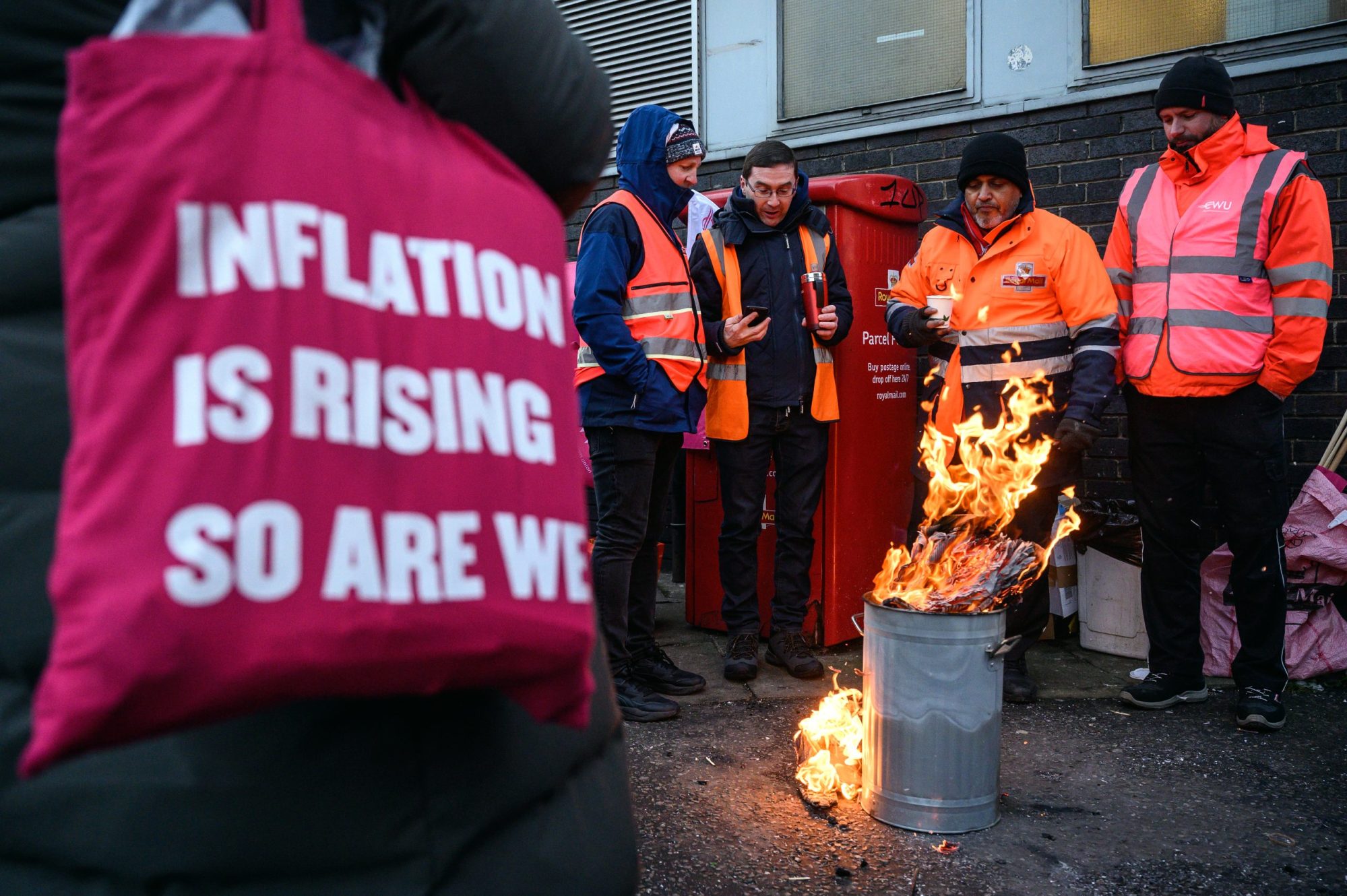 Men standing around fire holding a sign.