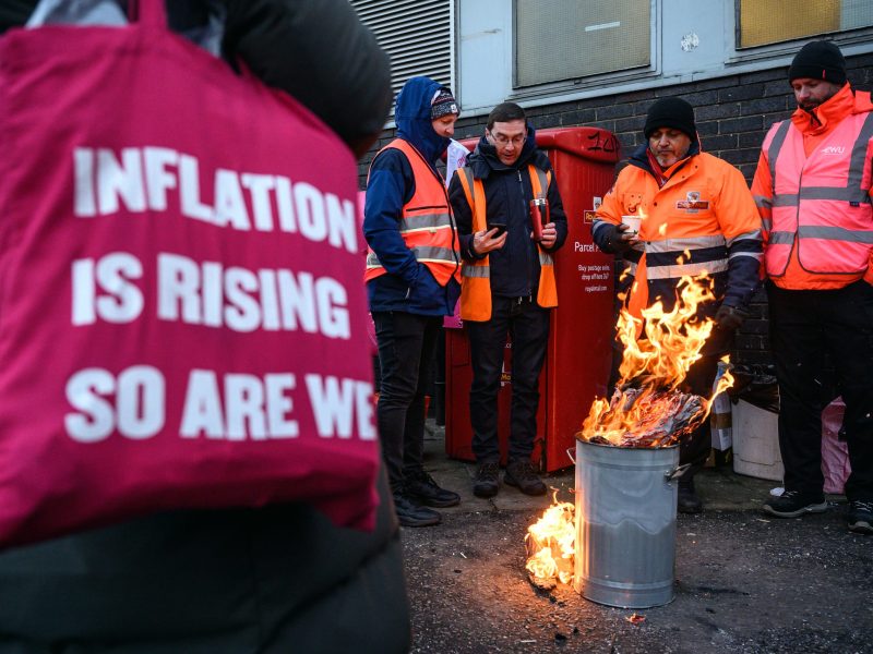 Men standing around fire holding a sign.
