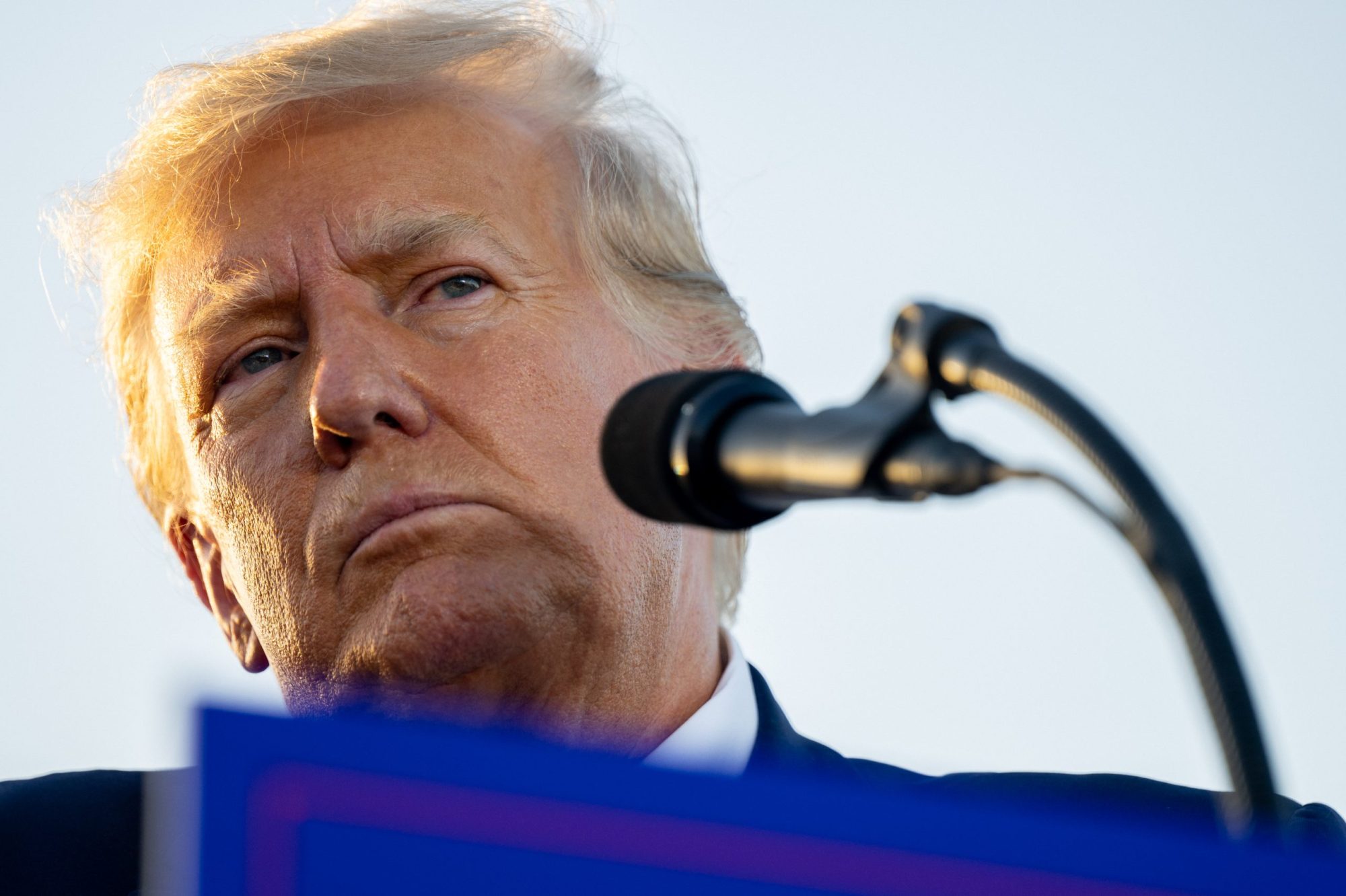 Close up of Donald Trump's face. He is grimacing in front of a microphone.