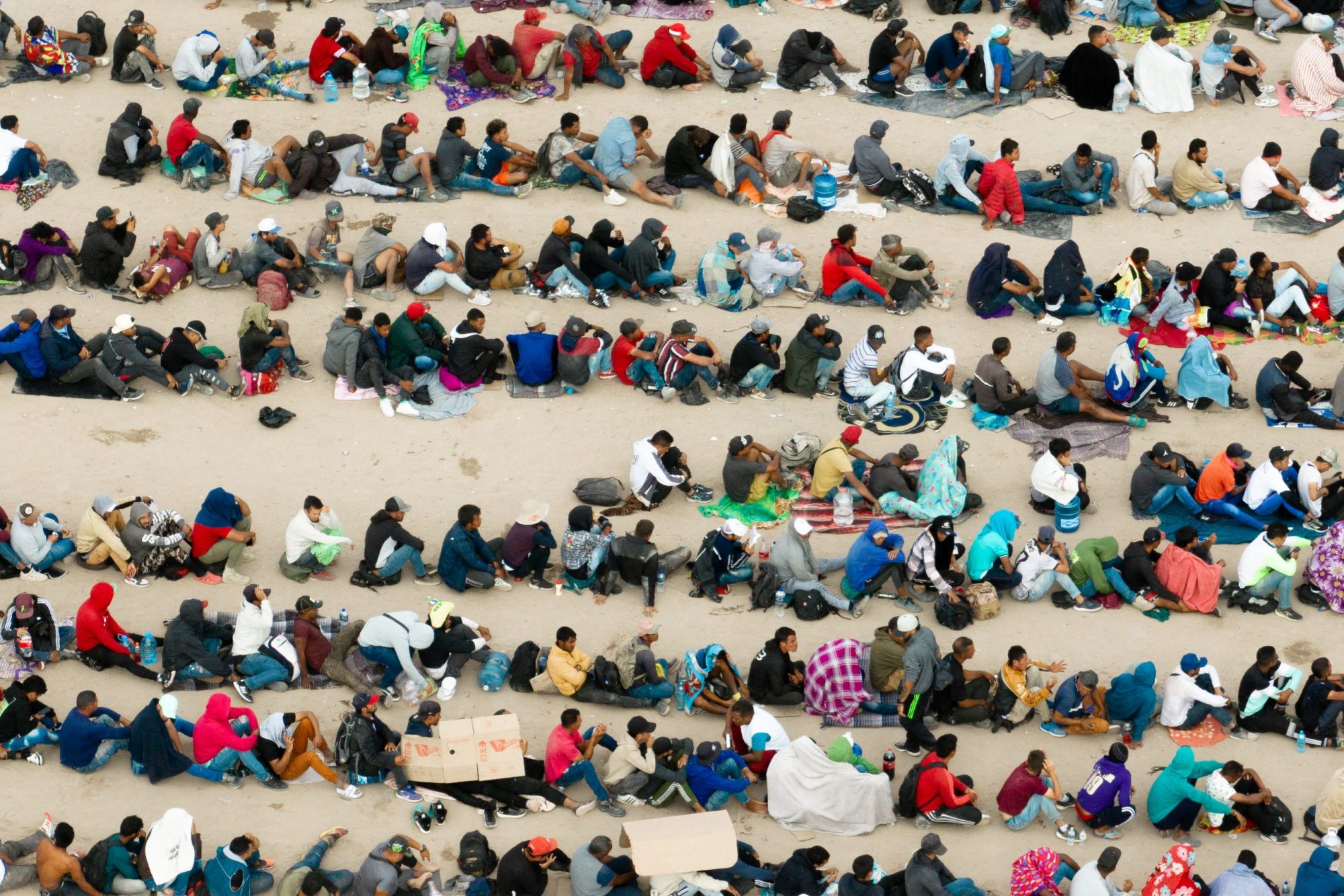 In an aerial view, migrants are seen grouped together while waiting to be processed on the Ciudad Juarez side of the border on Sept. 21, 2023, in El Paso, Texas.