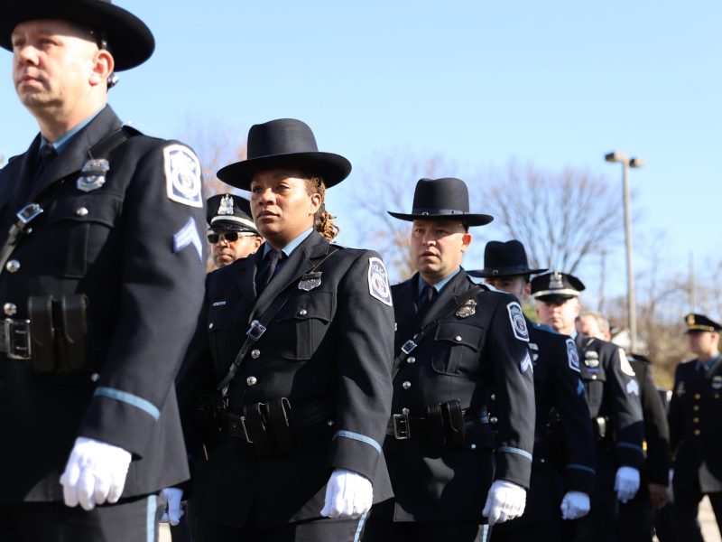 A line of police marching in formal uniforms