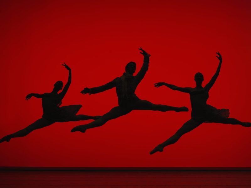 Three ballet dancers leaping on stage, silhouette