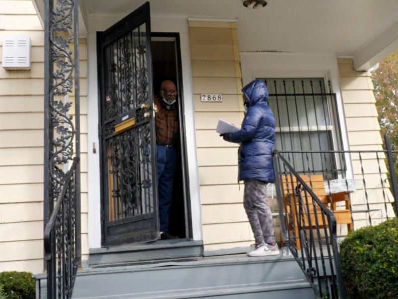 A canvasser speaks to a voter at their front door